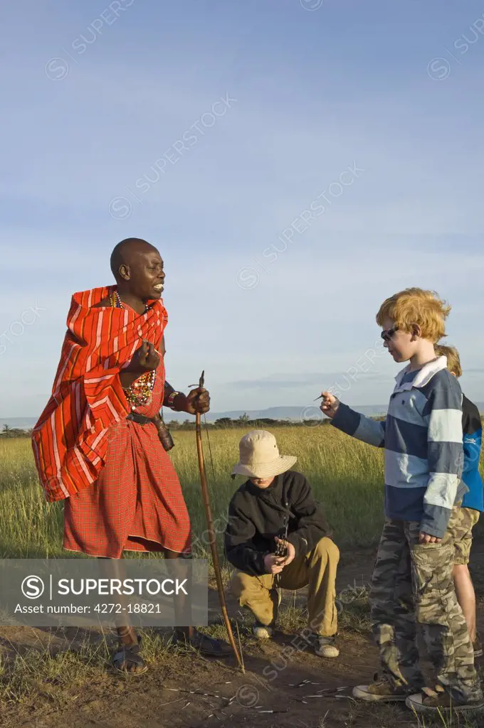 Kenya, Masai Mara.  Safari guide, Salaash Ole Morompi, shows porcupine quills to young boys on a family safari. (MR)