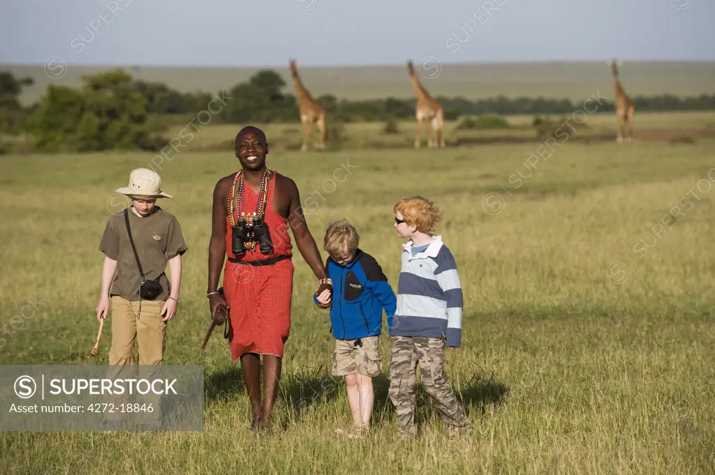 Kenya, Masai Mara.  Safari guide, Salaash Ole Morompi, leads boys on a bush walk across the plains. (MR)