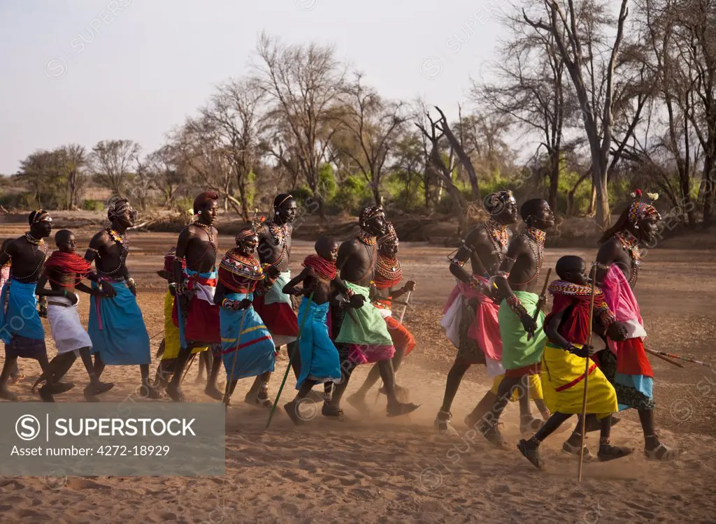 Kenya, Samburu District.  Samburu warriors and young girls sing and dance in the dry river bed of the Ewaso Nyiro River.