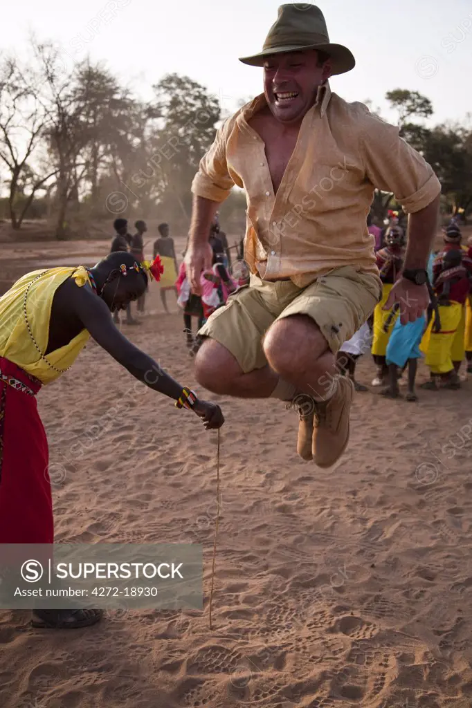 Kenya, Samburu District.  A tourist attempting to jump as high as a Samburu warrior, in the dry river bed of the Ewaso Nyiro.