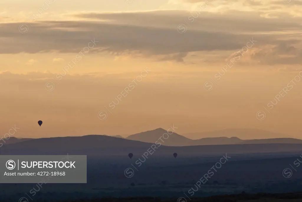 Dawn breaks over Masai-Mara as hot air balloons drift over the plains.