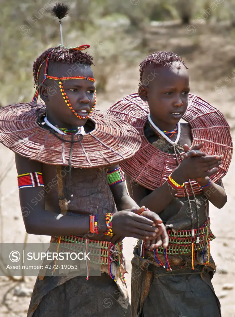 Two young Pokot girls wearing traditional ornaments that denote their unmarried status. Their broad belts are made with the metacarpus and metatarsal bones of dikdiks interspersed with beads. Kenya