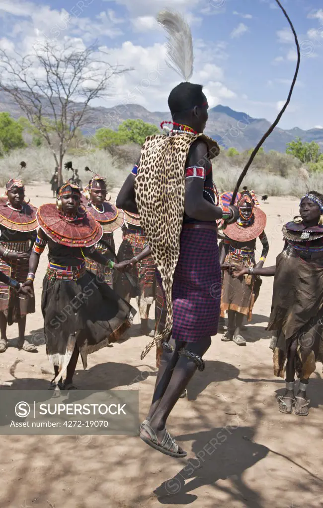 A Pokot warrior wearing a leopard skin jumps high in the air surrounded by women to celebrate an Atelo ceremony. The Pokot are pastoralists speaking a Southern Nilotic language.