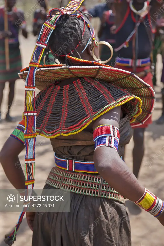 A Pokot woman in traditional attire dances to celebrate an Atelo ceremony. Her broad belt is made with the metacarpus and metatarsal bones of dikdiks interspersed with beads.