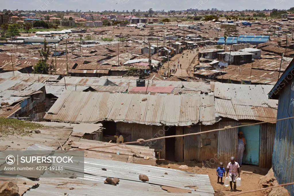 Kibera is the biggest slum in Africa and one of the largest in the world. It houses about one million people in cramped, unhygienic conditions on the outskirts of Nairobi. Modern high-rise flats are visible in the distance.