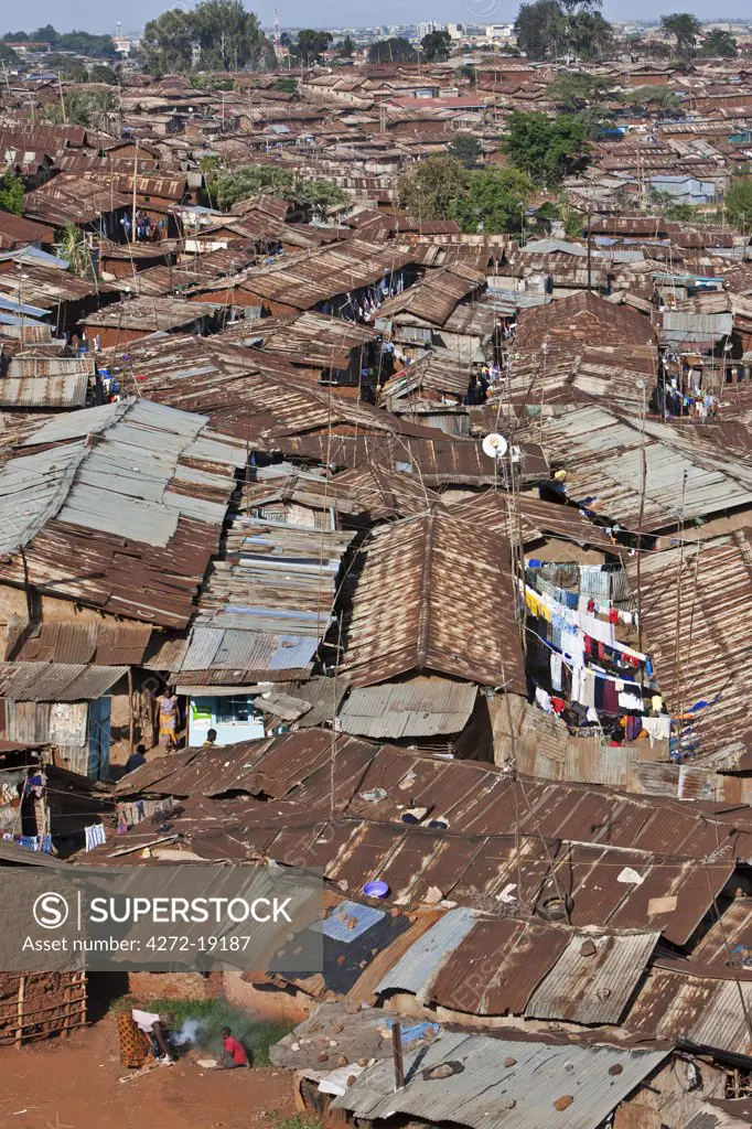 Kibera is the biggest slum in Africa and one of the largest in the world. It houses about one million people in cramped, unhygienic conditions on the outskirts of Nairobi. Modern high-rise buildings of the city centre are visible in the distance.