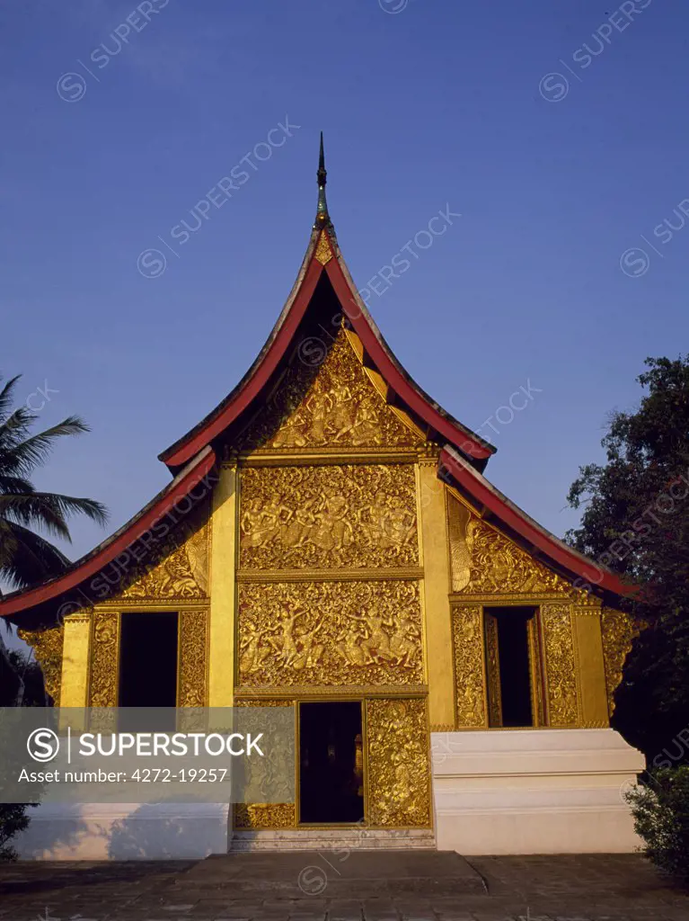 Laos, Luang Prabang Province, Luang Prabang. Royal funeral carriage chapel at Wat Xieng Thong, the Golden City Temple.  Inside is an impressive 12 metre long funeral carriage and urns for each member of the royal family.  The gilt panels on the exterior of the chapel depict semi-erotic episodes from the Ramayana.