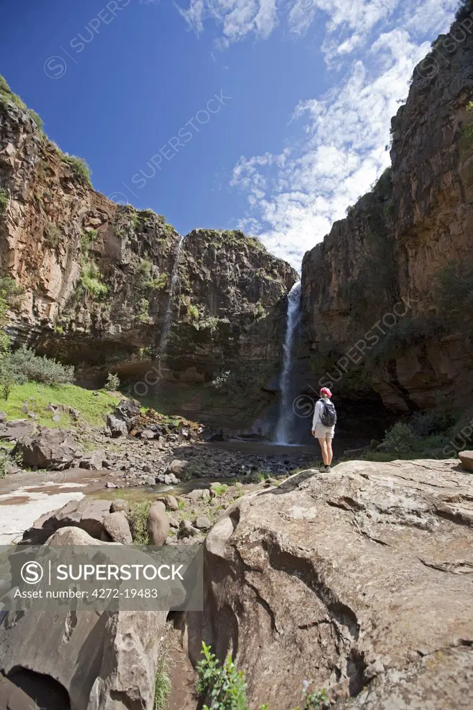 Lesotho, Malealea. A tourist looks at a waterfall whilst on a trek from Malealea. MR