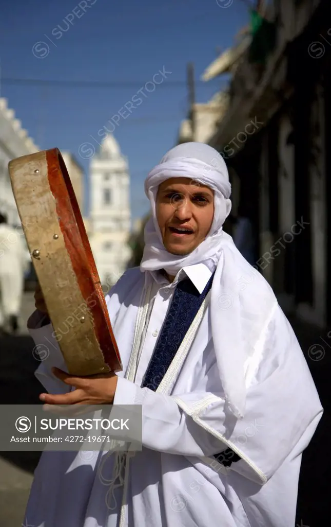 Libya, Tripolitania, Tripoli; A man in white silk with a tambour, during the Mawlid festivities celebrating Prophet Mohammeds birth