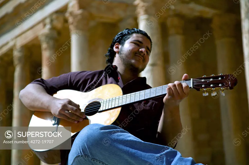 Sabratha, Libya; A young guitarist playing in front of the Theatre remains at Sabrata