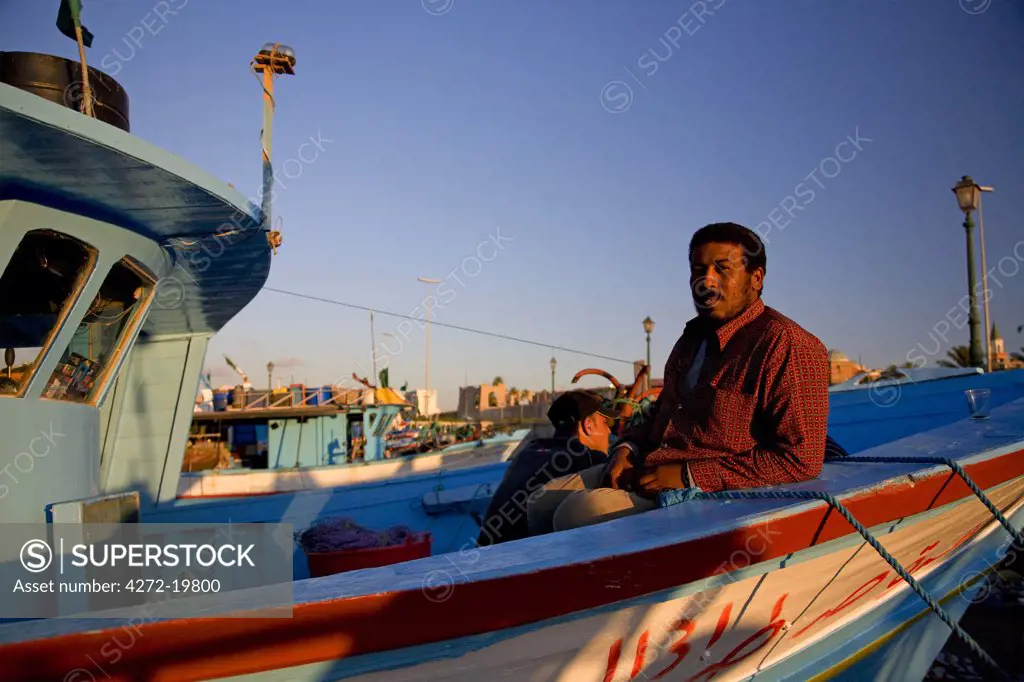 Tripoli, Libya; An Egyptian man posing for a photograph on his fishing boat in the port of Tripoli