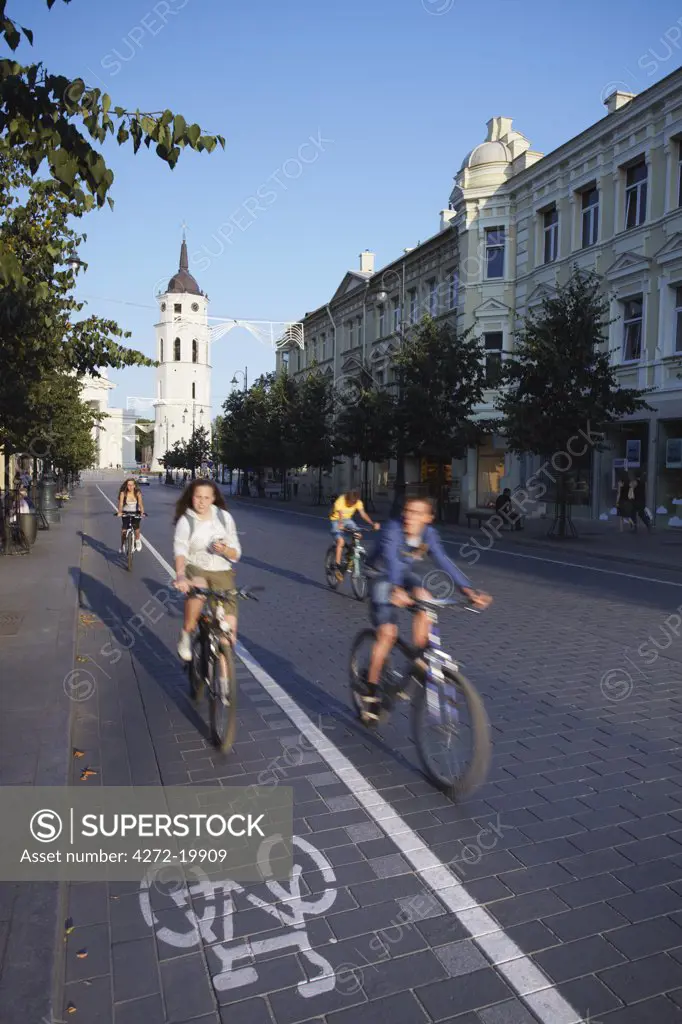 Lithuania, Vilnius, Children Cycling Along Gedimino Prospektas With Vilnius Cathedral Bell Tower In Background