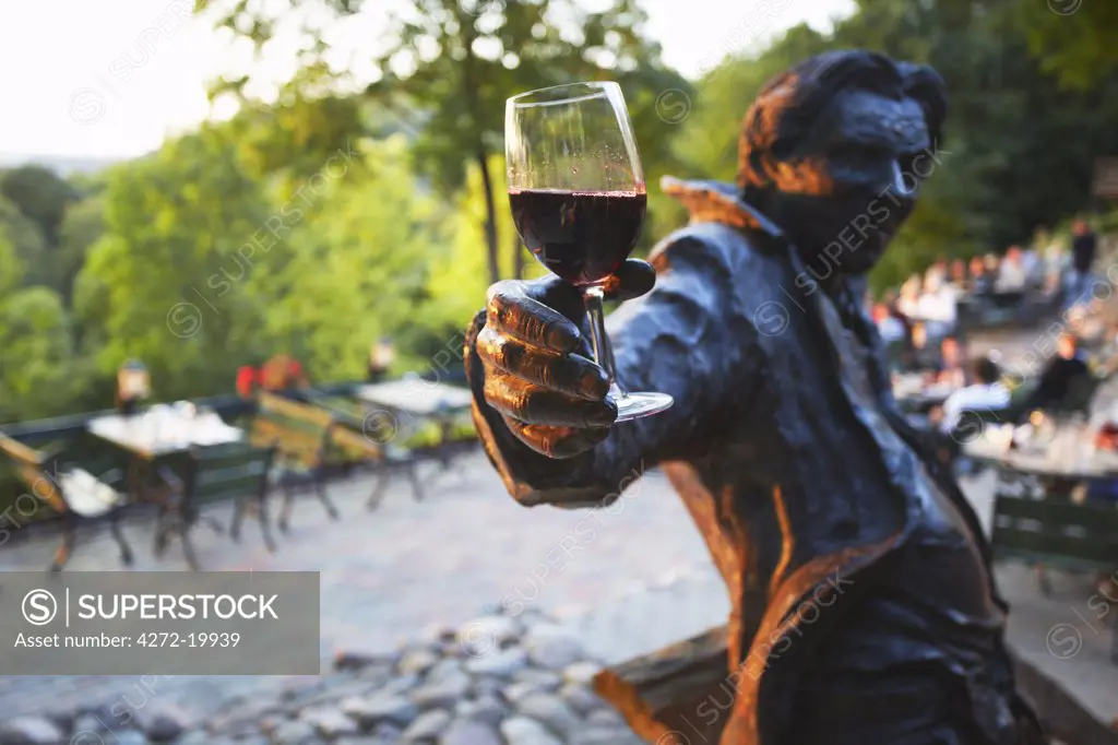 Lithuania, Vilnius, Uzupis District, Statue Holding Glass Of Red Wine At Outdoor Patio At Tores Restaurant