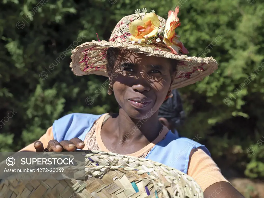 A woman wearing a decorated Malagasy hat sells baskets in Ambalavao market.