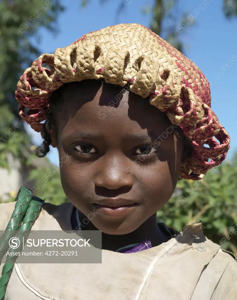 A young Malagasy girl wearing a local raffia hat.