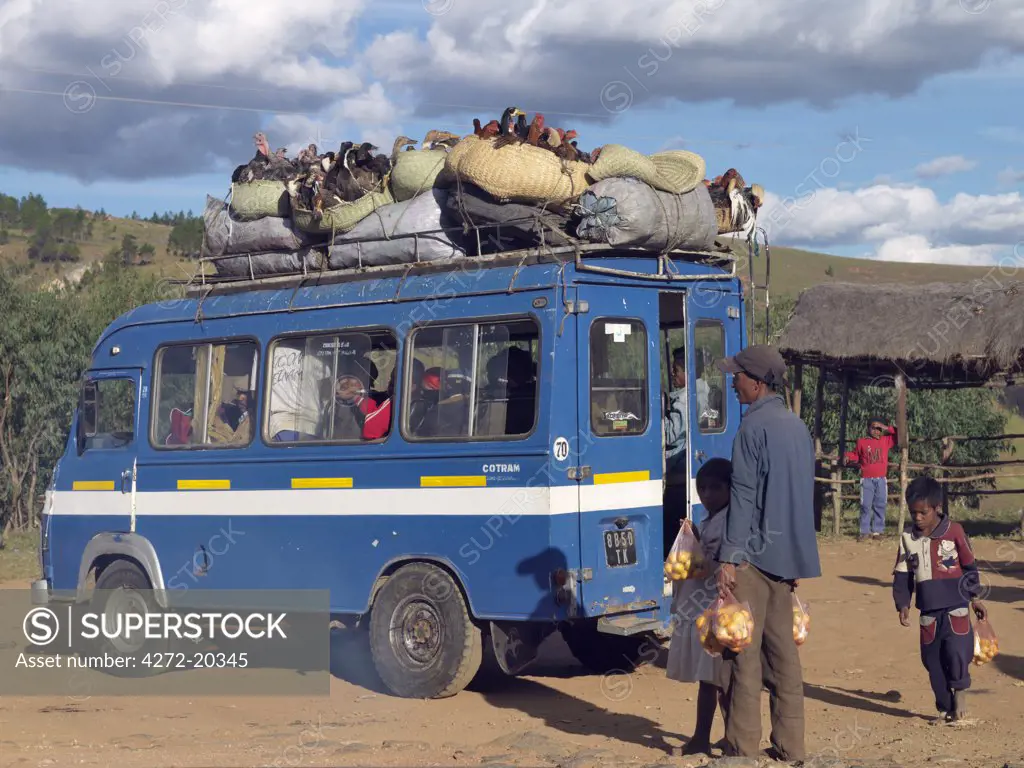 A taxi-brousse stops to pick up passengers on its way to Antananarivo, capital of Madagascar. Turkeys, ducks and chickens are carried in baskets on top of the vehicle.