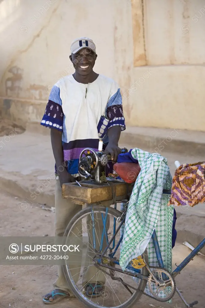 Mali, Segou. An enterprising tailor makes the rounds of his customers with his sewing machine strapped to the carrier of his bicycle.