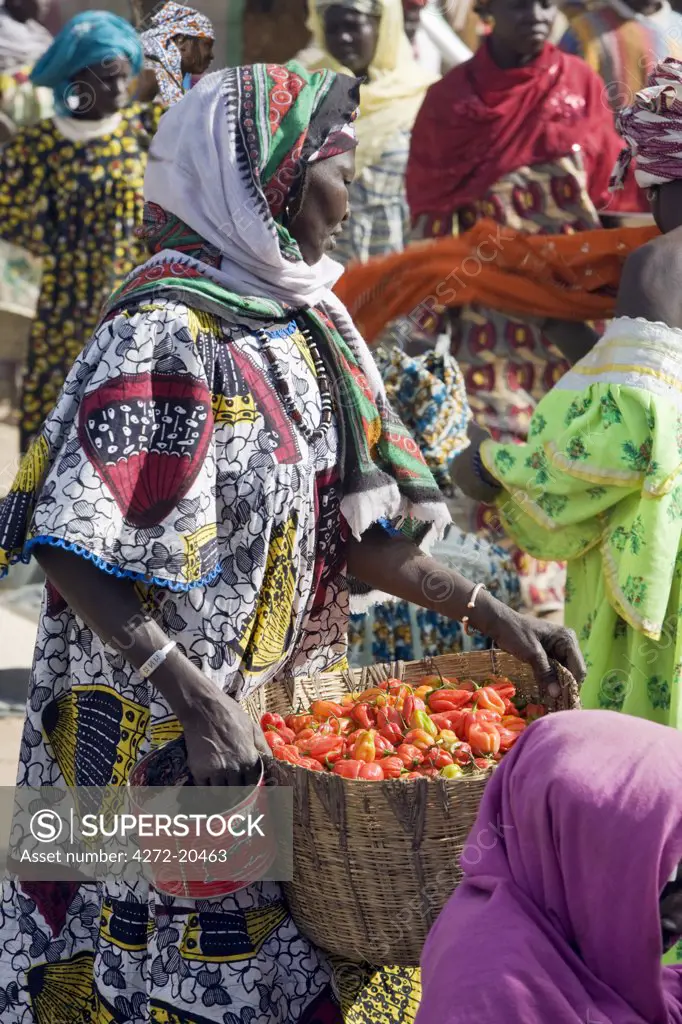 Mali, Djenne. A woman carries a basket of red chillies at Djenne market. The weekly Monday market is thronged by thousands of people and is one of the most colourful in West Africa.