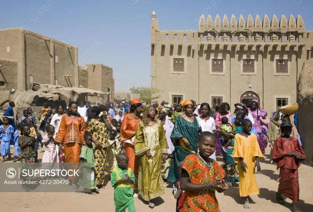 Mali, Djenne. Wedding guests make their way through Djenne. With a population of about 10,000, Djenne is an agricultural town situated on an island in the Niger Inland Delta. Beautiful mud-brick buildings are a feature of this historic place.
