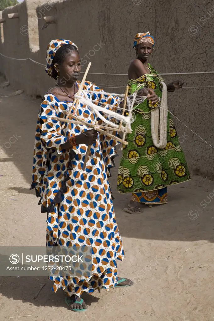 Mali, Senossa. Two Peul women prepare skeins of cotton yarn from the long lengths they had spun round the walls of their home. Mali is Africa's second largest cotton producer.