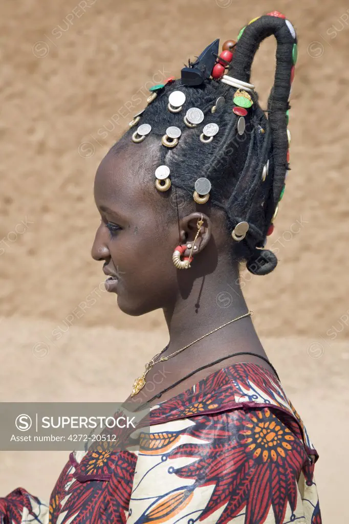 Mali, Gao. A Songhay woman at Gao market with an elaborate coiffure typical of her tribe. The silver coins are old French francs and British West Africa coins dating back one hundred years.