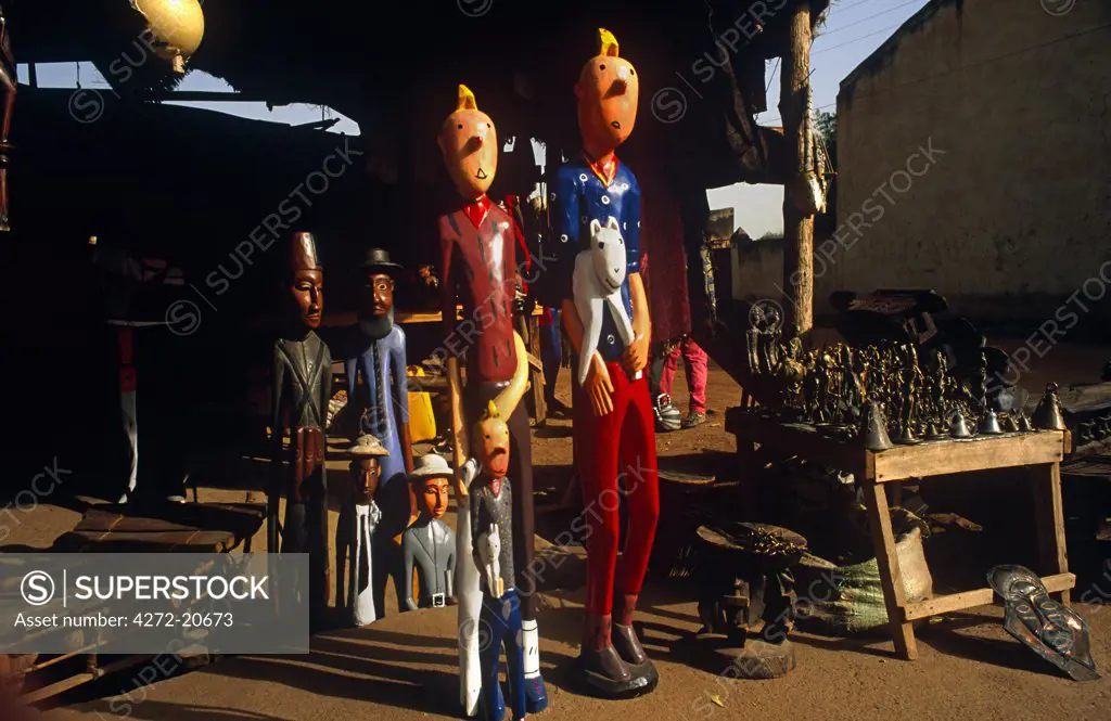 Mali, Segou. Wooden Tintin statues are offered for sale at a craftman's stall by the River Niger at Segou.