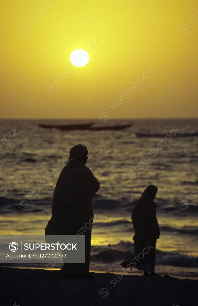 Mauritanian women shrouded in melafas are silhouetted against the afternoon sun at the Plage des Pecheurs (Fishermen's Beach) near Nouakchott.,,,