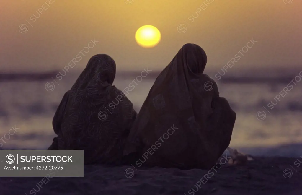 MAURITANIA, Nouakchott Mauritanian women shrouded in melafas are silhouetted against the afternoon sun at the Plage des Pecheurs (Fishermens Beach) near Nouakchott.