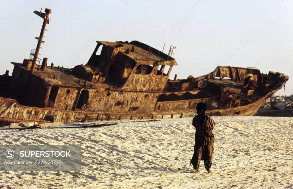 MAURITANIA, Nouakchott A local man walks past the rusting hulk of a shipwrecked freighter buried in the sands of the Plage des Pecheurs (Fishermens Beach) near Nouakchott.