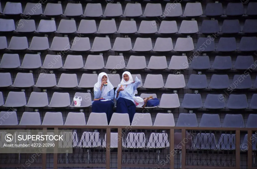 Two religiously dressed girls in sports stadium stand