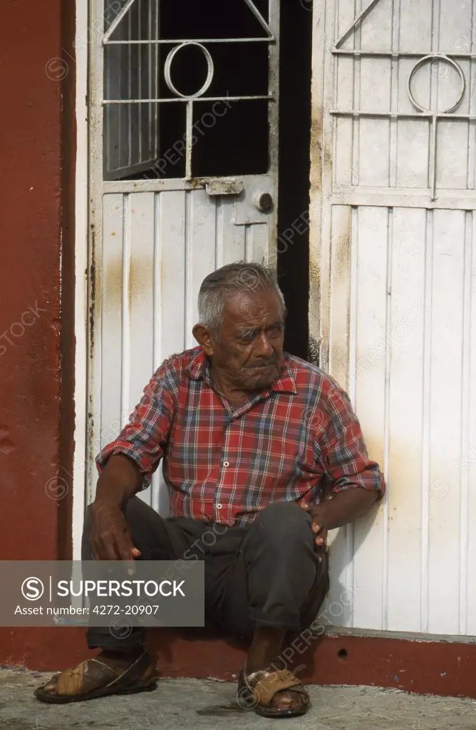 Man sitting in doorway of house in the street.