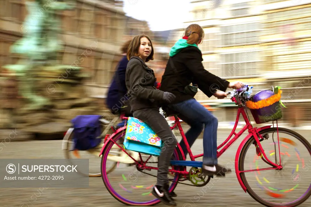 Belgium, Flanders; Antwerp; Girls Cycling Through Antwerp's Main Square.