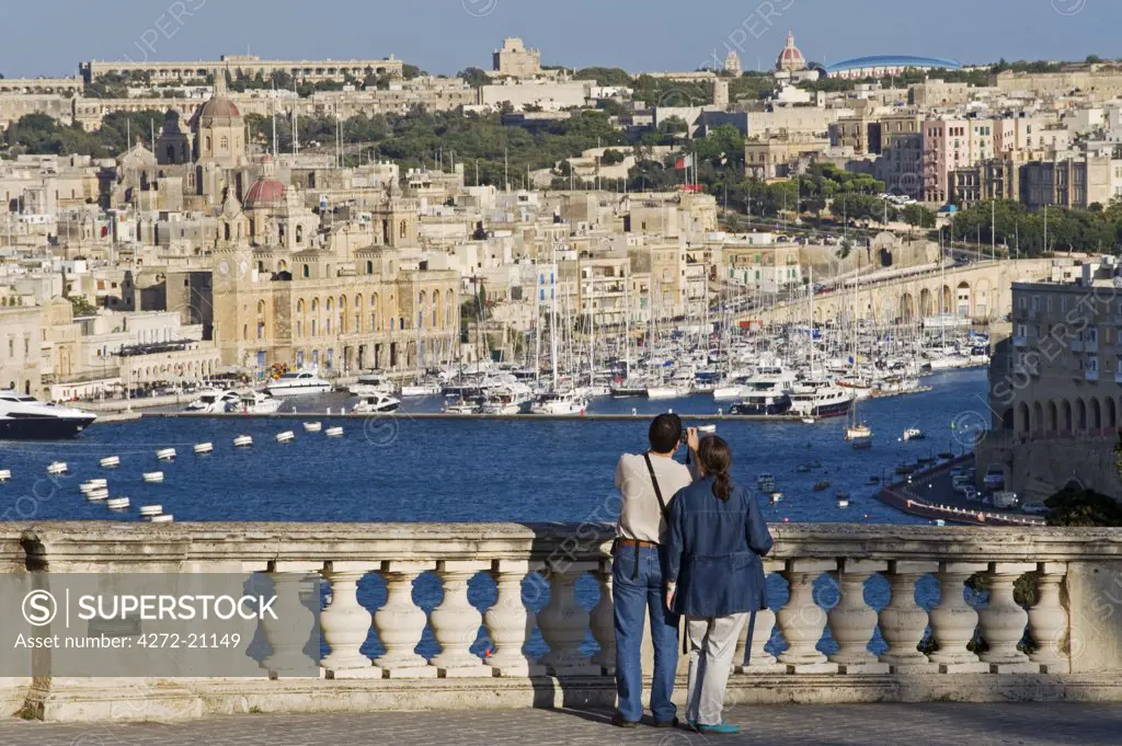 Malta, Valletta.  Tourists look out from an elegant ballustrade on the old walls of Valletta over the Grand Harbour towards Vittoriosa
