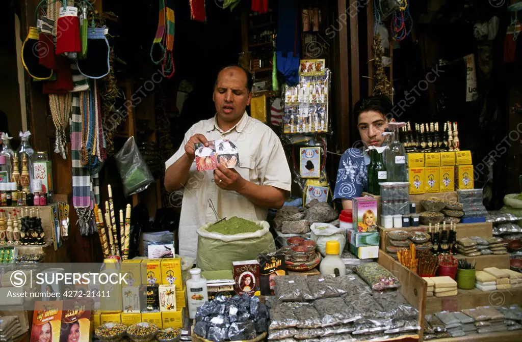 A stallholder holds up a picture of hennaed hands at his stall in the Souk au Henne