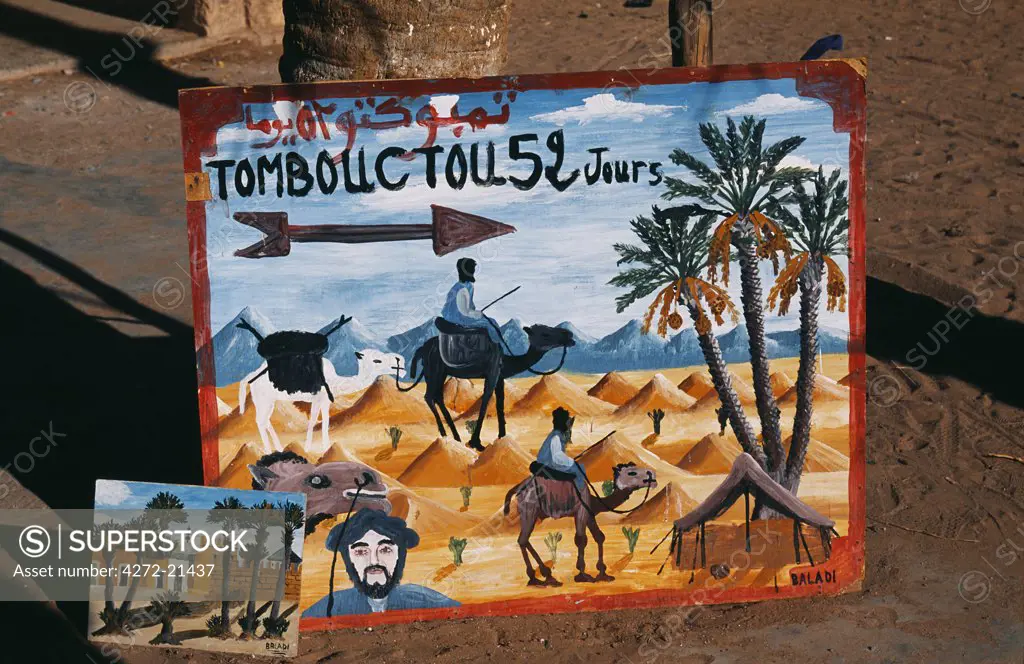 Painted sign pointing to Tomboutou, Timbuktu and 52 days by camel in the town of Mohammed, Draa Valley, Ouazazate Province, Southern Morocco.