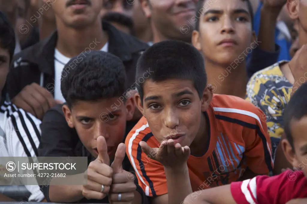 Morocco, Fes. Two boys in the crowd at a concert during the Fes Festival of World Sacred Music blow kisses.