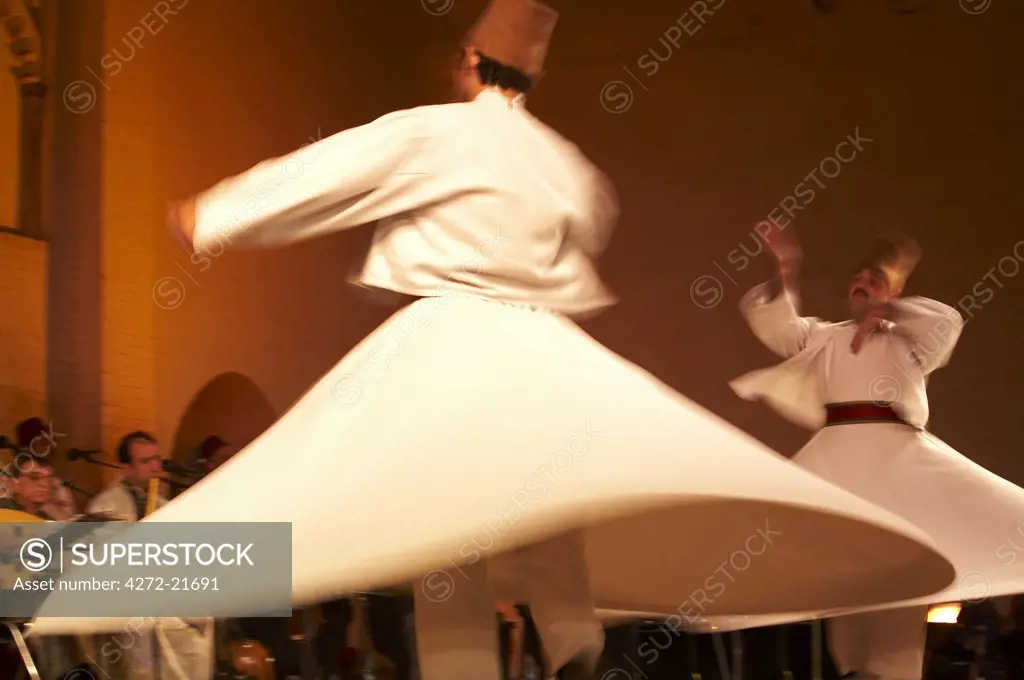 Morocco, Fes.  Two whirling Dervishes perform during a concert at the Fes Festival of World Sacred Music.  Members of the Al Kindi Ensemble perform the music.