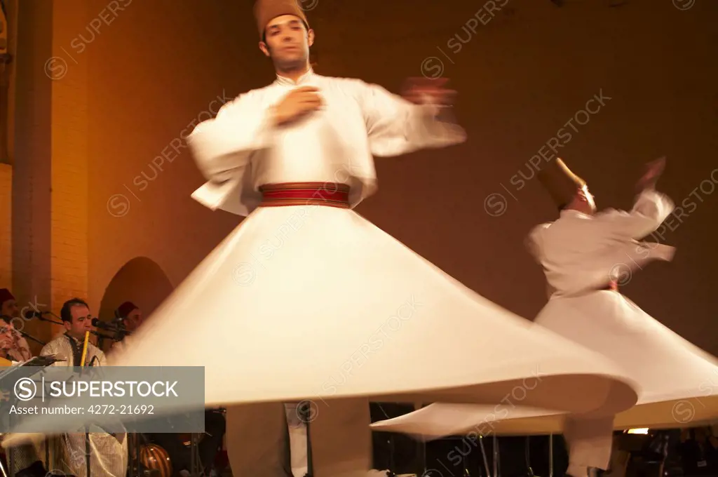 Morocco, Fes. Two whirling Dervishes perform during a concert at the Fes Festival of World Sacred Music. Members of the Al Kindi Ensemble perform the music.