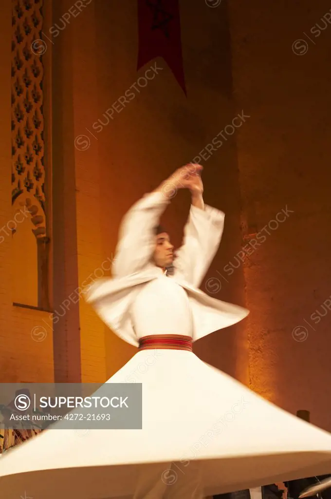 Morocco, Fes. A whirling Dervishe performs on the stage at the Bab Makina during a concert at the Fes Festival of World Sacred Music. Members of the Al Kindi Ensemble perform the music.