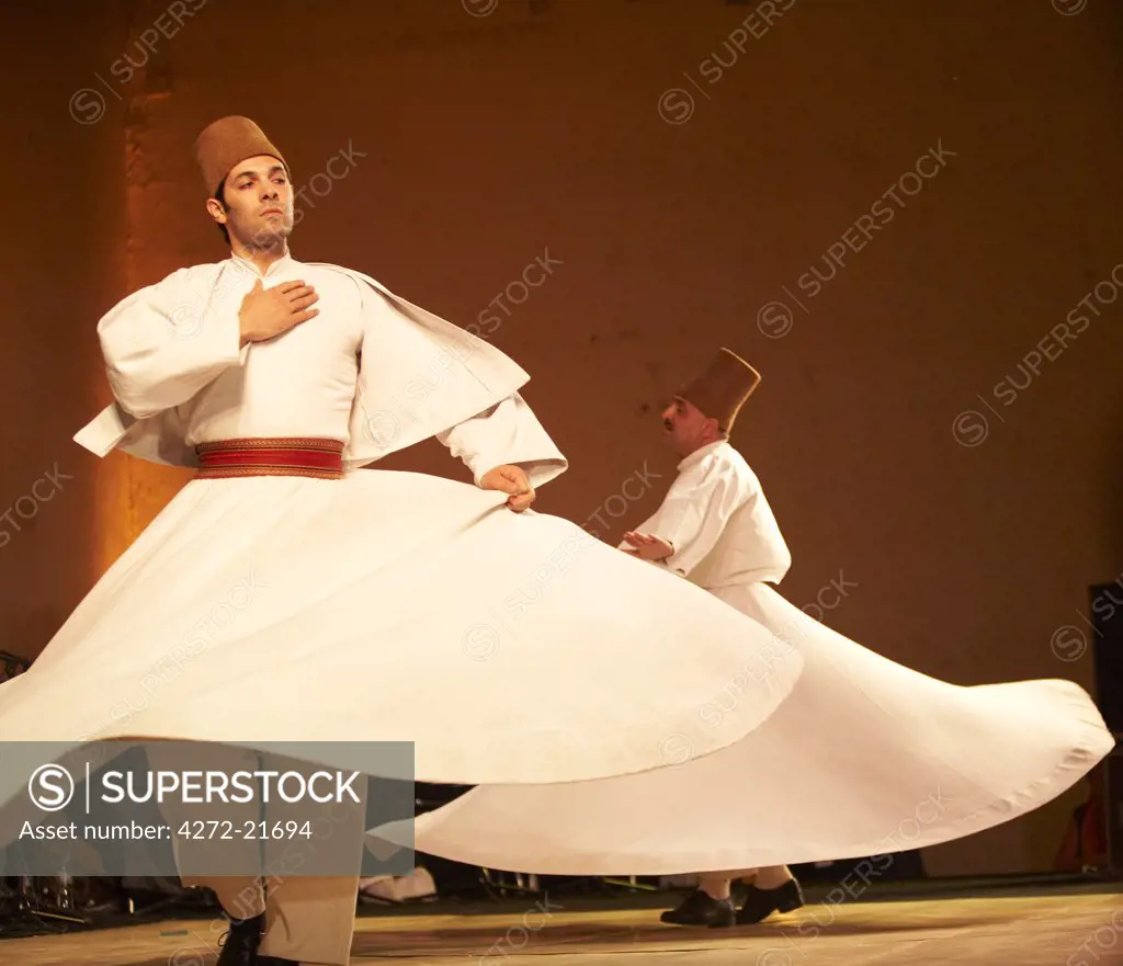 Morocco, Fes.  Two whirling Dervishes perform during a concert at the Fes Festival of World Sacred Music.  Members of the Al Kindi Ensemble perform the music.