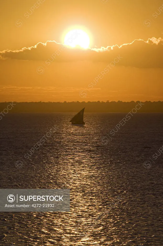 A dhow sails past the Ilha do Mozambique at sunset.