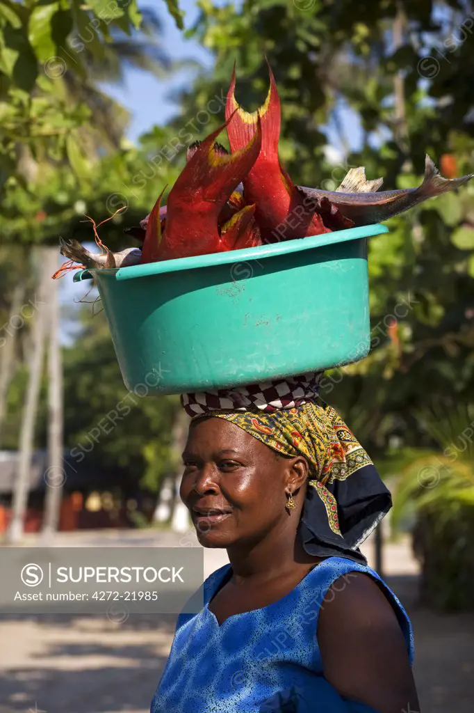 Mozambique, Inhaca Island.  A local African lady carries her catch of fish on her head, in Inhaca village on Inhaca Island.  Inhaca Island is the largest island in the Gulf of Maputo, and lies 24km from the mainland.