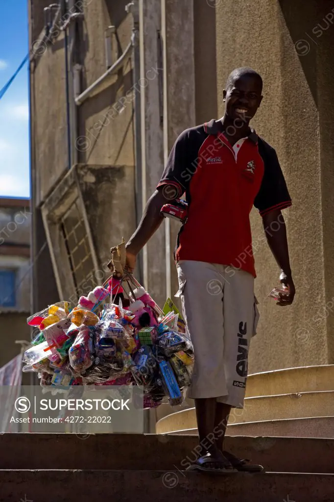 Mozambique, Maputo. A street vendor carries his products around the Polana district of Maputo - including toys, sweets and hair styling products. Maputo is the capital of Mozambique. It is a bustling, attractive port city with a population of at least 1.5 million.  Maputo is a very agreeable city which is considerably safe and more attractive when compared to other African capitals.