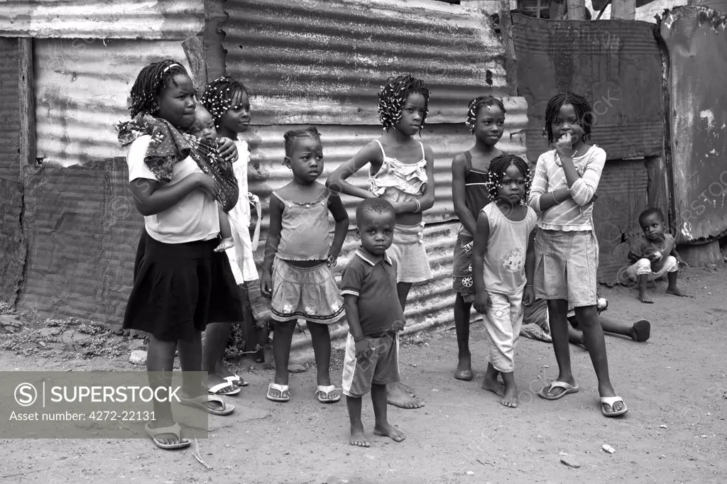 Mozambique, Maputo. A group of children crowd round the corrugated houses of their Canisa.