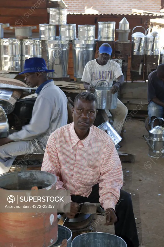 Malawi, Zomba. In the covered market, a group of blacksmiths work as a team to produce domestic holdhold goods