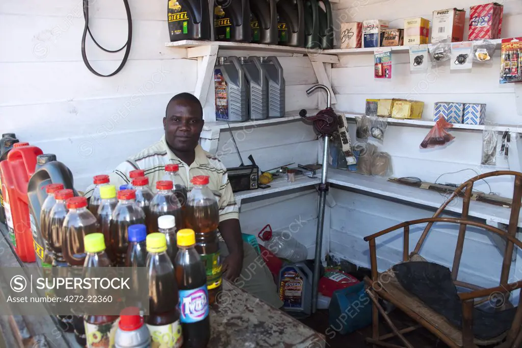 Malawi, Zomba. In the market area, selling motor oils and spare parts, a shop owner relaxes behind his counter.