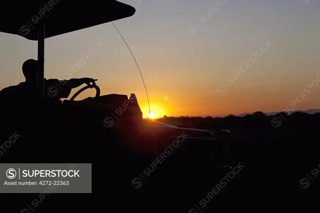 Malawi, Upper Shire Valley, Liwonde National Park. At sunset a tour guide points out of a shaded safari vehicle.
