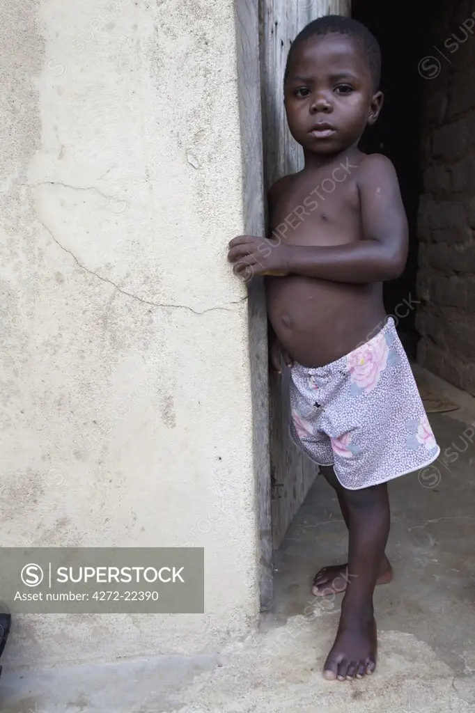 Malawi, Lake Malawi, Likoma Island. In the islands capital of Chipyela a young boy gazes shyly from the doorway of his home.