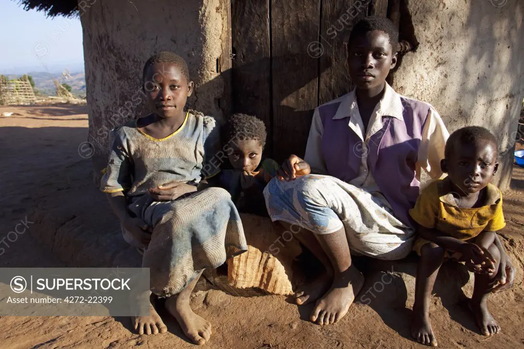 Malawi, Lilongwe, Ntchisi Forest Reserve. A young family sits by the entrance to their hut in a mountain village.