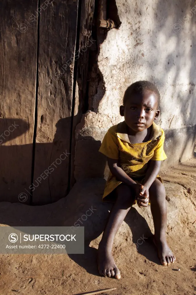 Malawi, Lilongwe, Ntchisi Forest Reserve. An small boy sits by the entrance to his house in a mountain village.